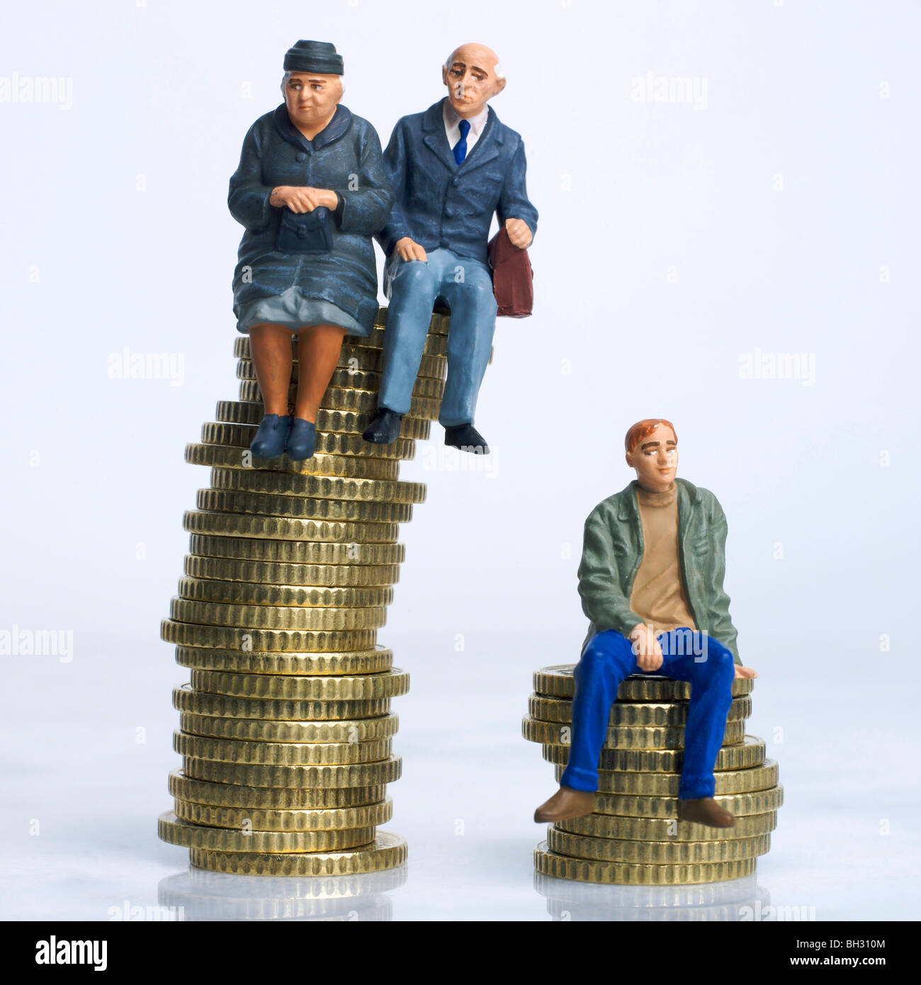 Old and young figures sitting on coins - inheritance / disparity in savings / pension money / old v young income concept Stock Photo