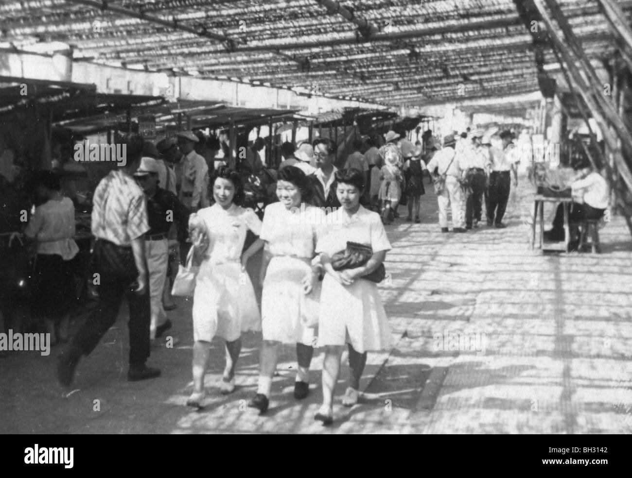 Young women walk under bomb netting in Post World War II Japan during the American occupation. Stock Photo