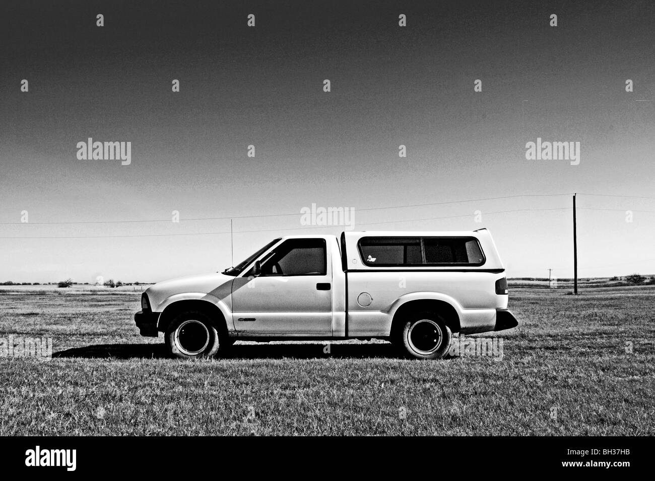 Older model 1994 Chevrolet pick up stands in dramatic contrast to the fresh, clean, clear atmosphere of the expansive grass land Stock Photo