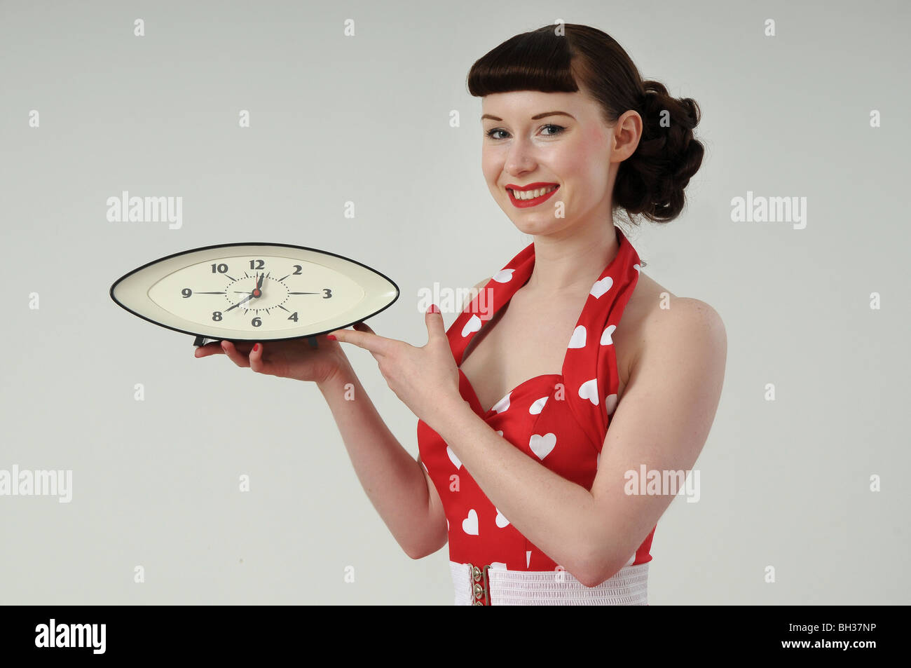 Pretty girl in 1950s style dress holding a clock Stock Photo