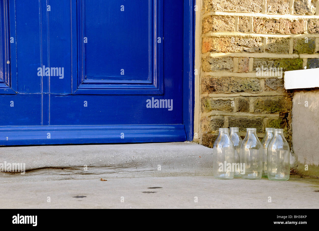 Five empty milk bottles on doorstep ready for collection, zero waste Stock Photo