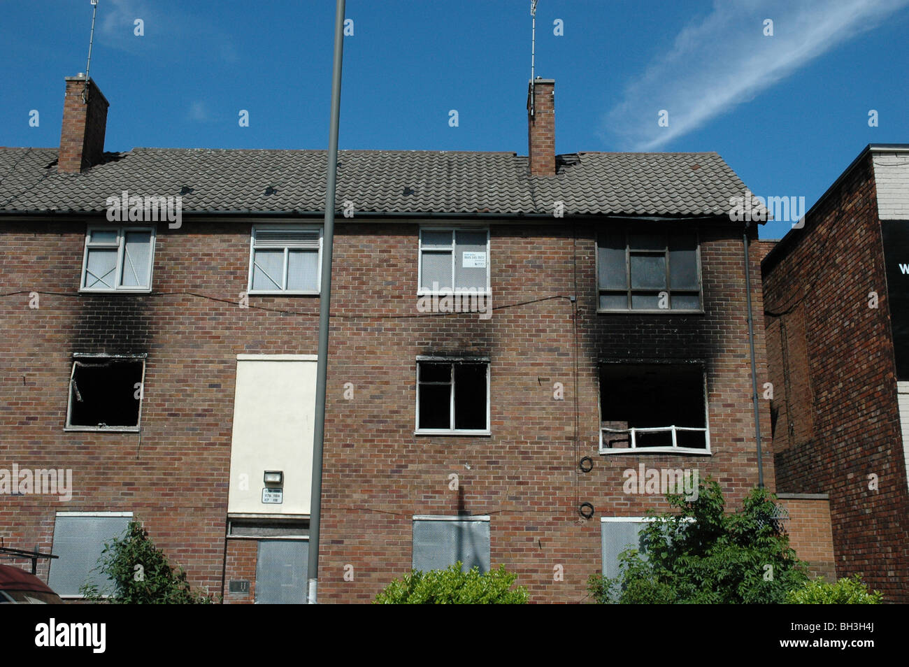 A fire damaged block of apartment flats.Some of the windows are boarded up and there is a lot of smoke damage. Stock Photo
