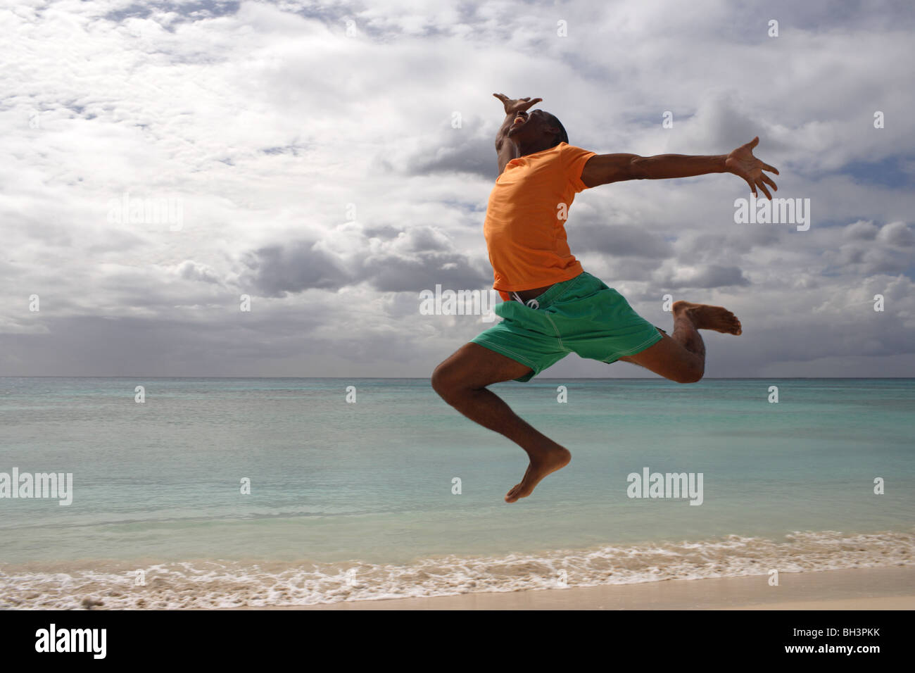 Young man leaping on a tropical beach, smiling Stock Photo