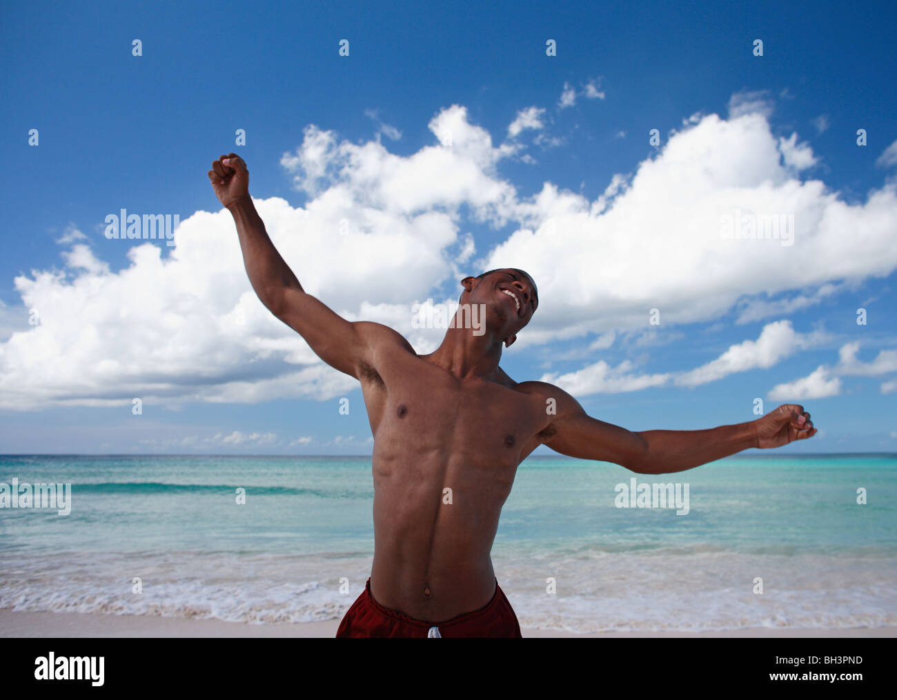 Young man dancing on tropical beach, smiling Stock Photo
