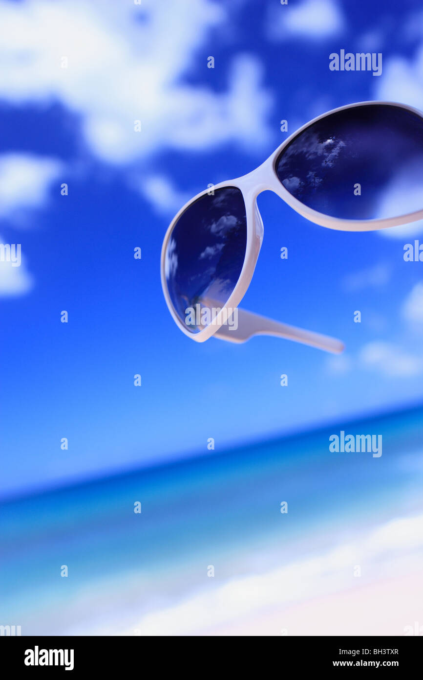 A pair of sunglasses against a tropical beach scene Stock Photo