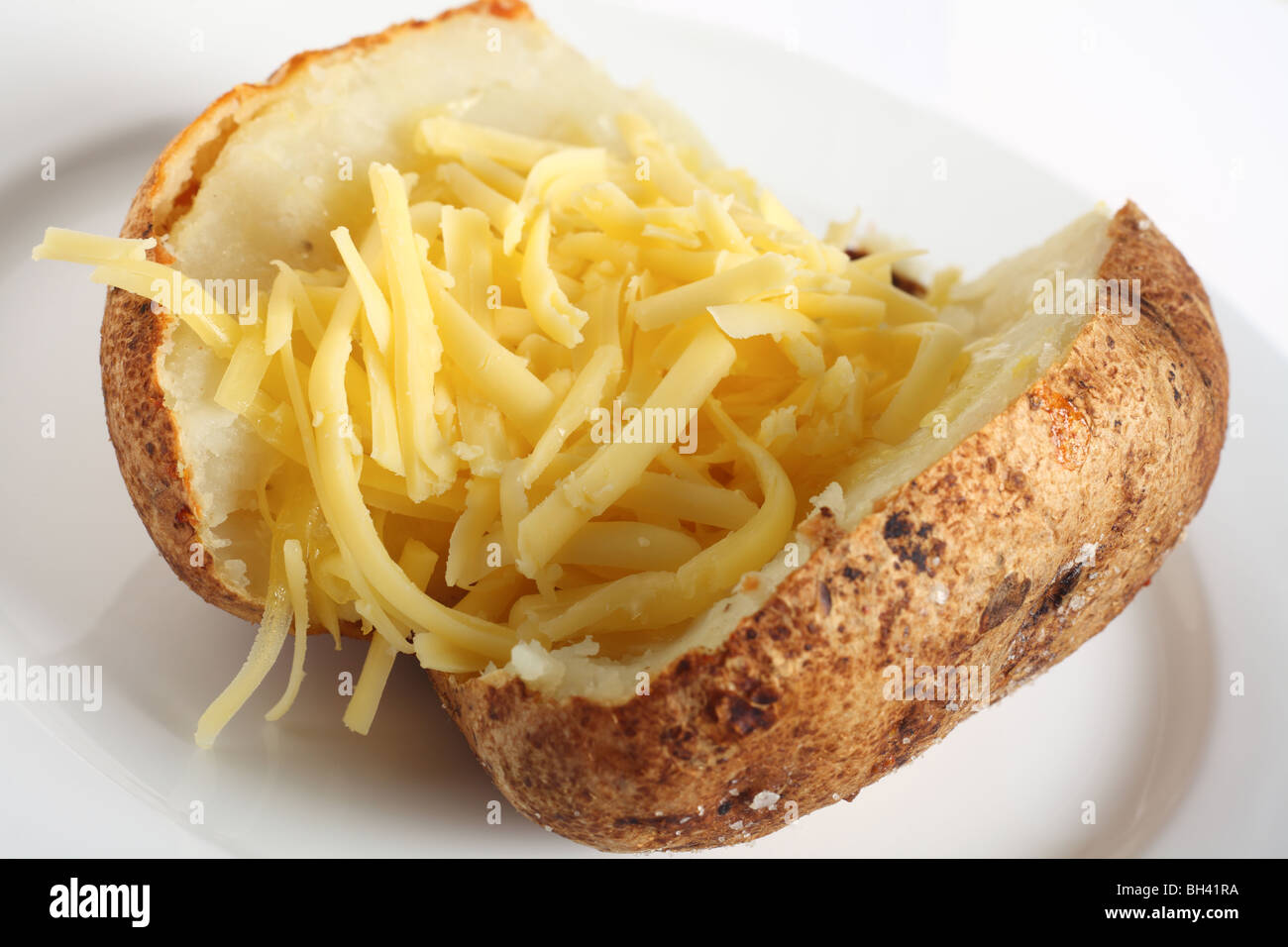 A baked russet potato stuffed with grated cheddar cheese, on a white