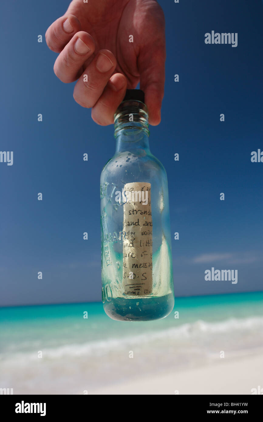 A man's hands holding a message in a bottle on a deserted tropical beach Stock Photo