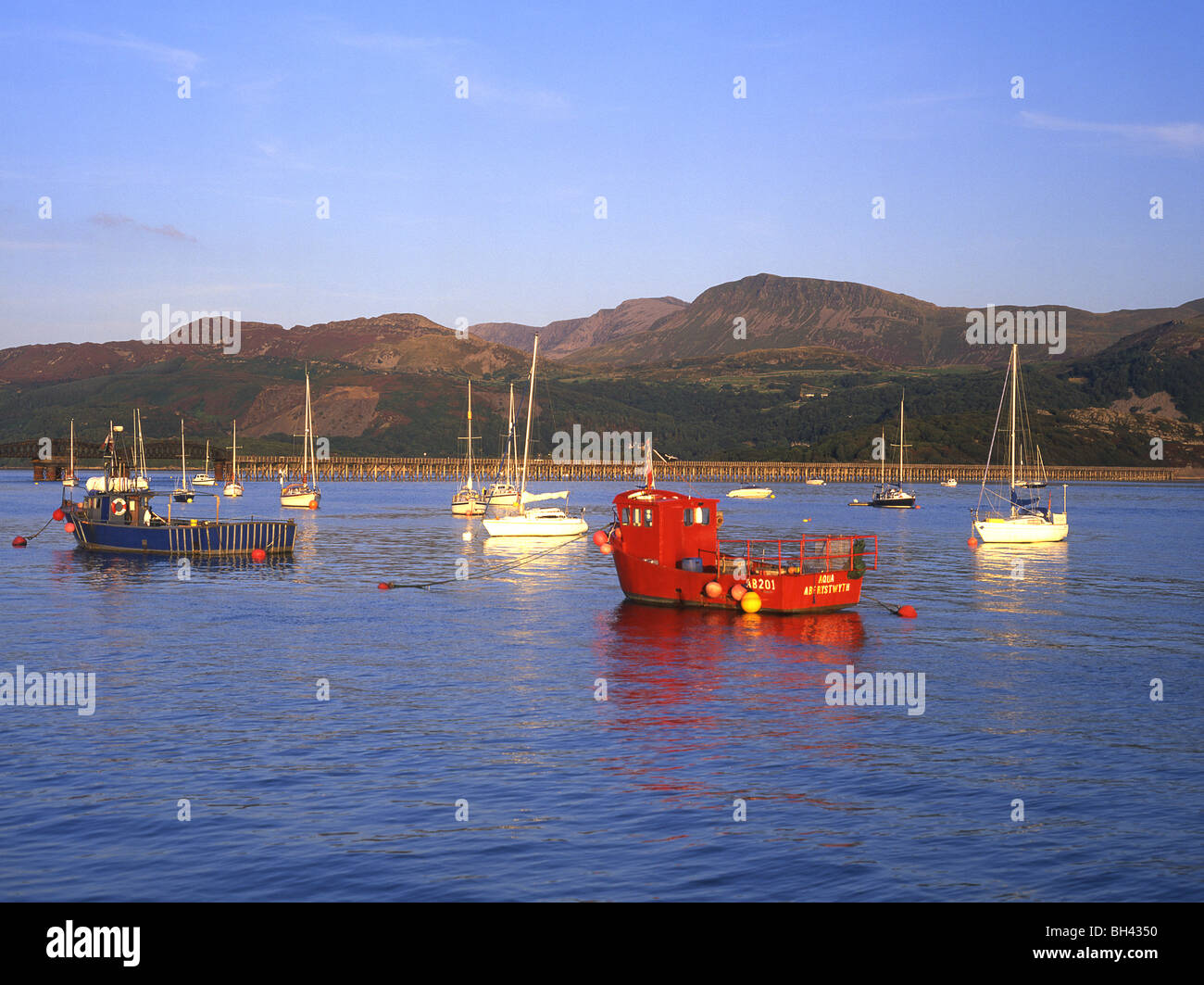 Boats in Barmouth harbour with railway bridge and Cadair Idris in ...