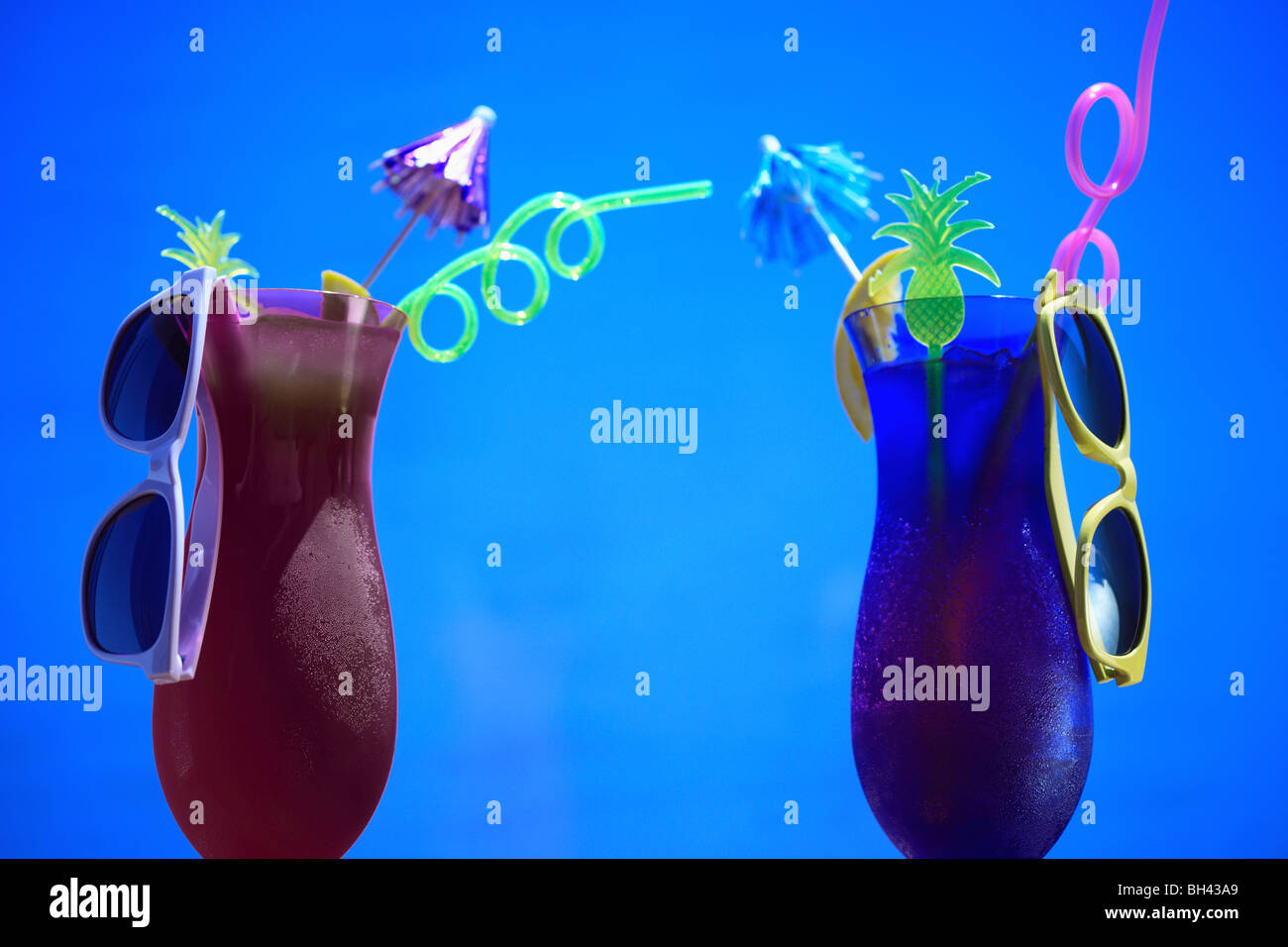A pair of tropical cocktails with sunglasses against a blue sky Stock Photo
