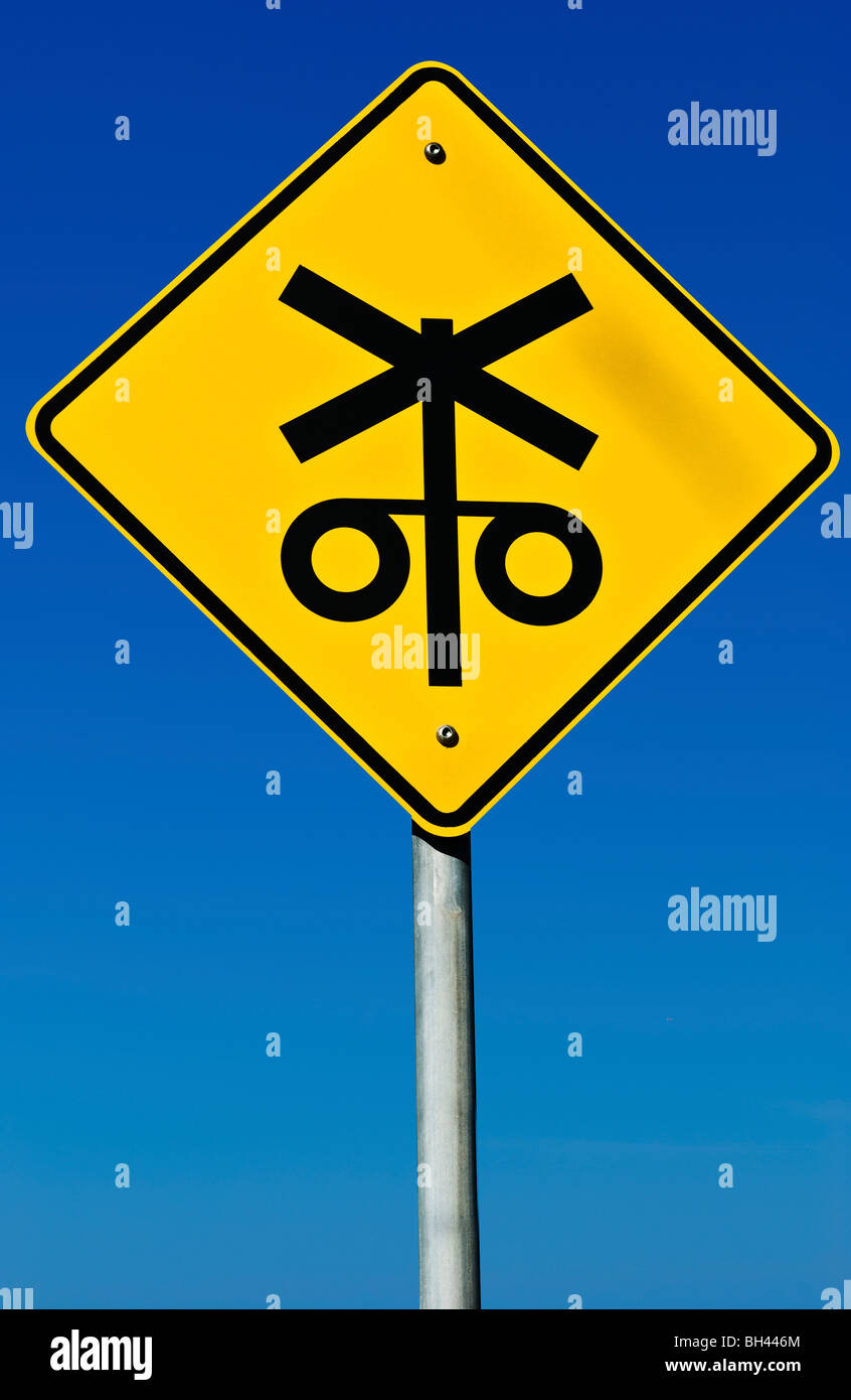 A railway crossing road sign isolated on a graduated blue background. Stock Photo