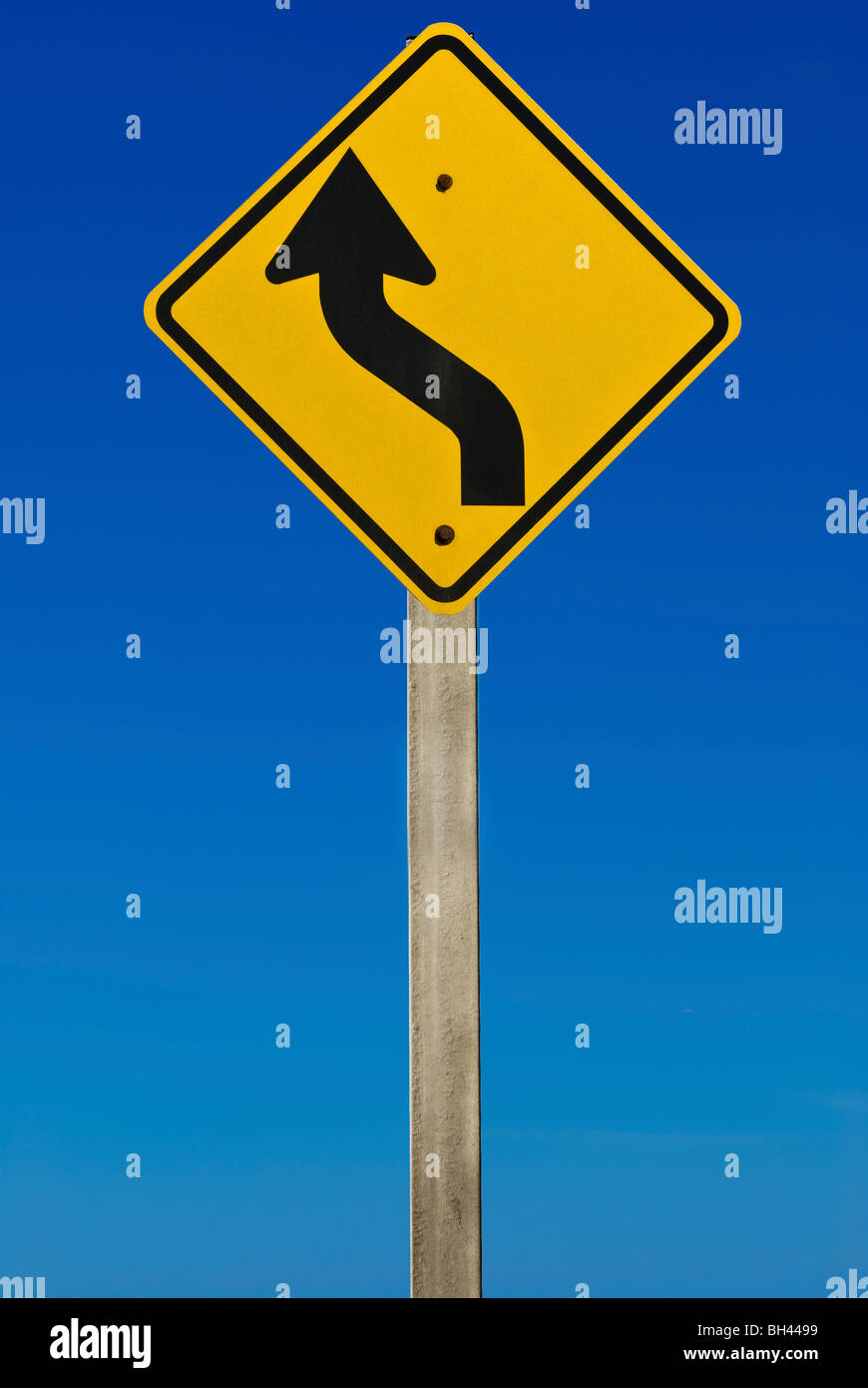 A road sign indicating a bend in the road. Isolated on a graduated blue background. Stock Photo