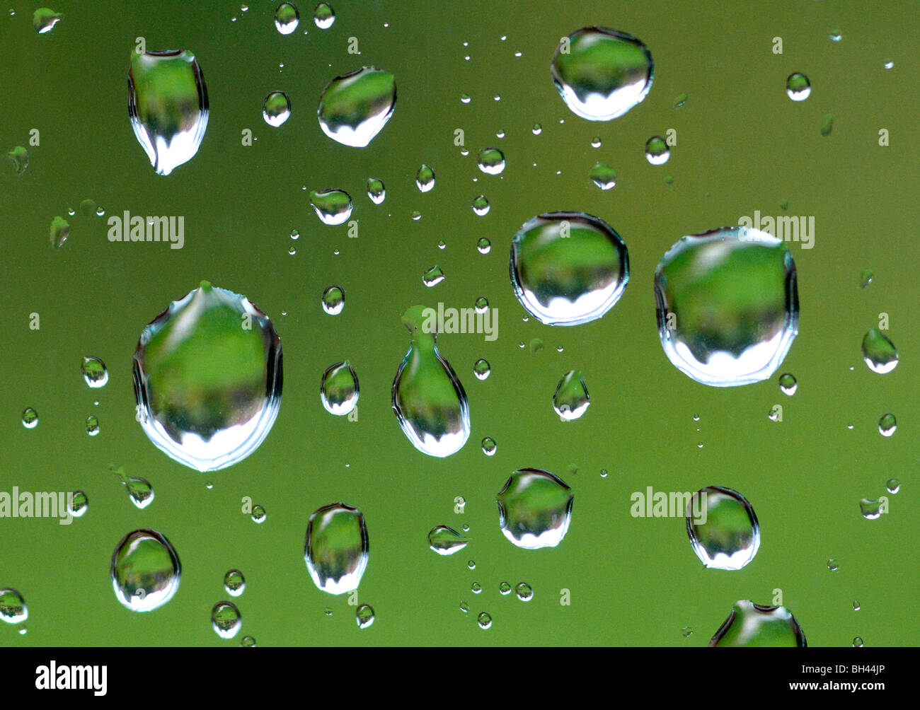 Close up of raindrops on window against green lawn background. Stock Photo