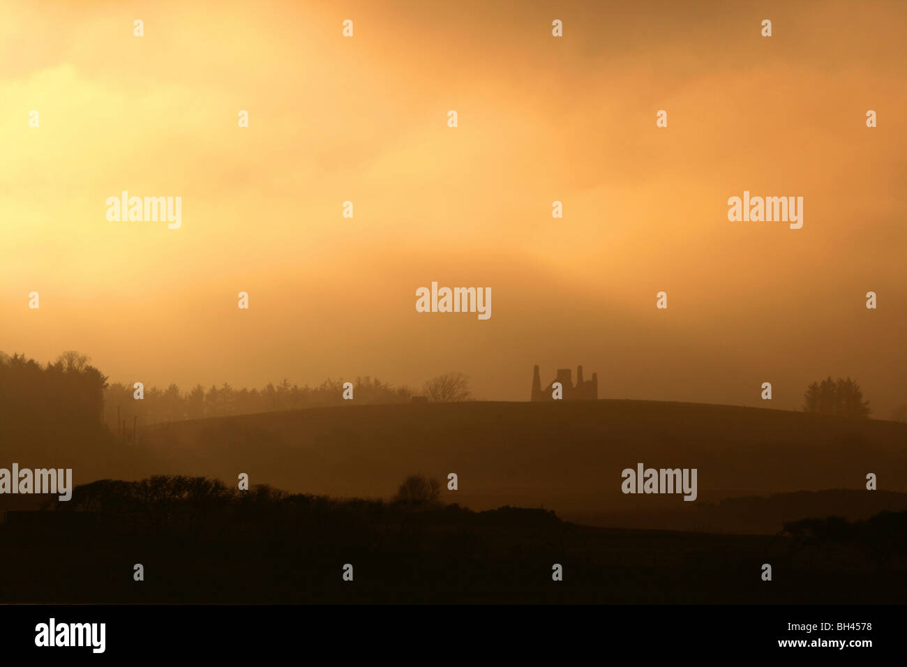 Ruins in rural landscape silhouetted against a misty sunset sky. Stock Photo