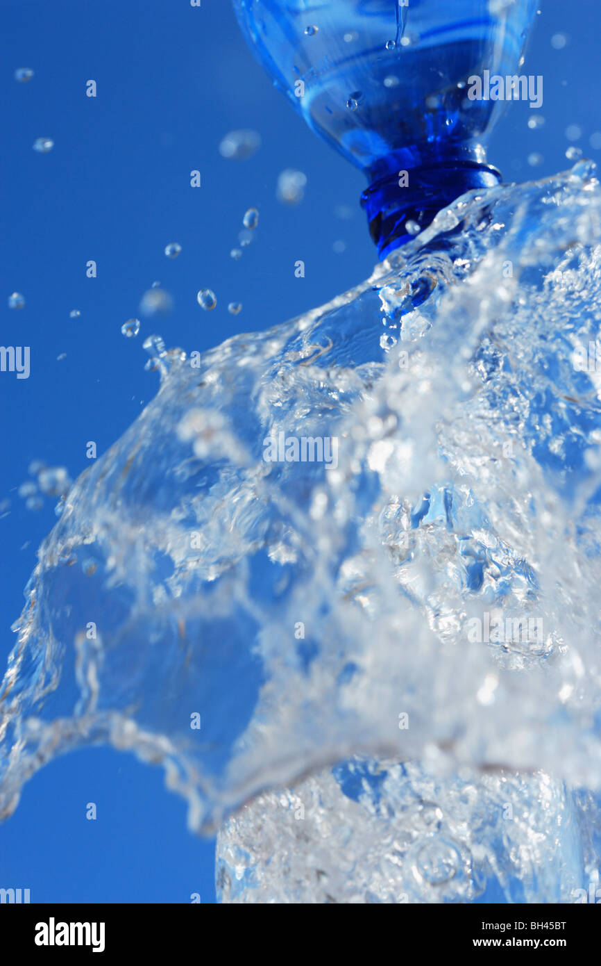 Water splashing from a bottle into a glass Stock Photo