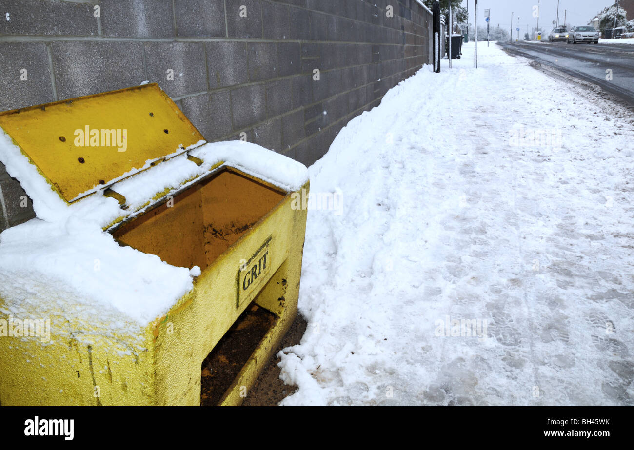 Snow covered and icy streets during uncommonly severe cold weather in the UK during the winter of 2009-2010 and a empty grit bin Stock Photo