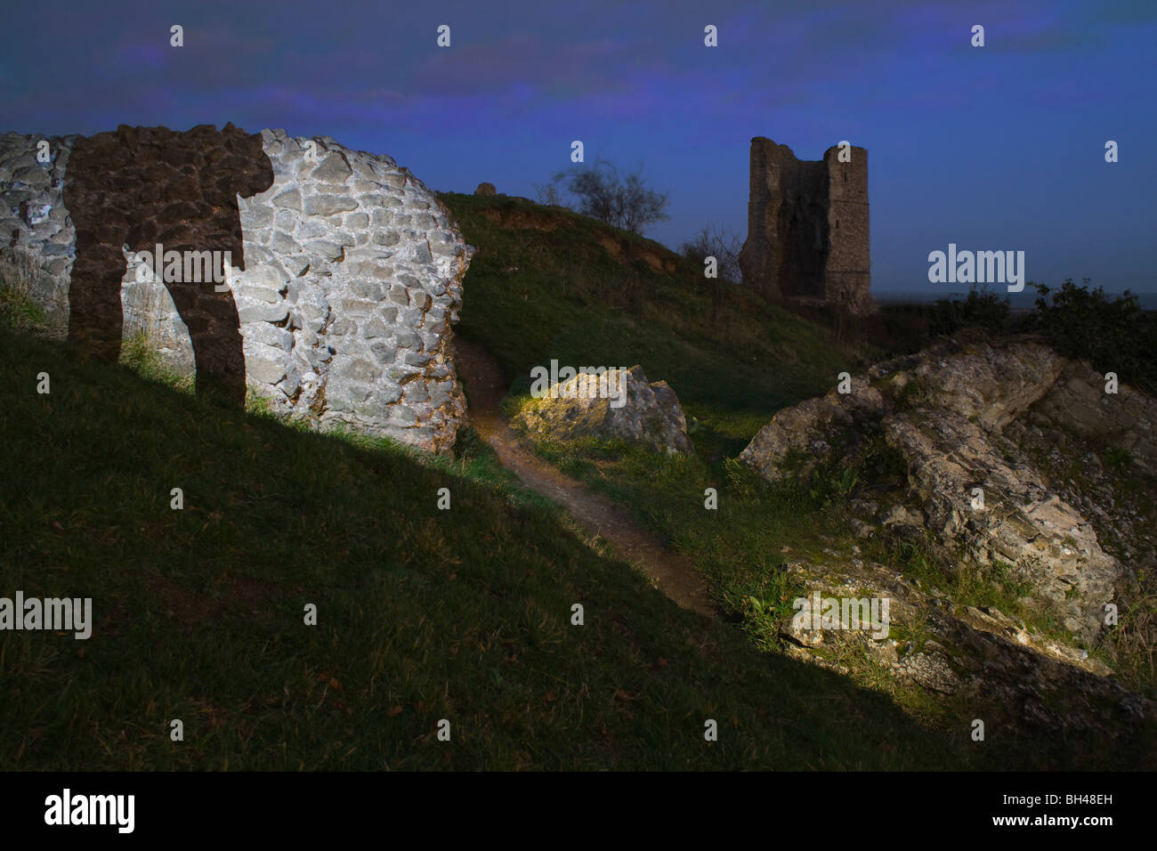 Ruined castle walls and tower of Hadleigh castle at twilight with lighting effects and a shadowy figure. Stock Photo