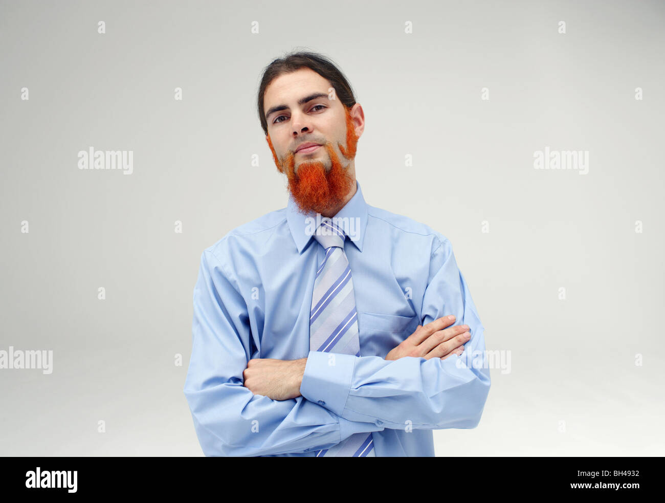 A young businessman with an orange beard wearing a blue shirt with a serious expression Stock Photo