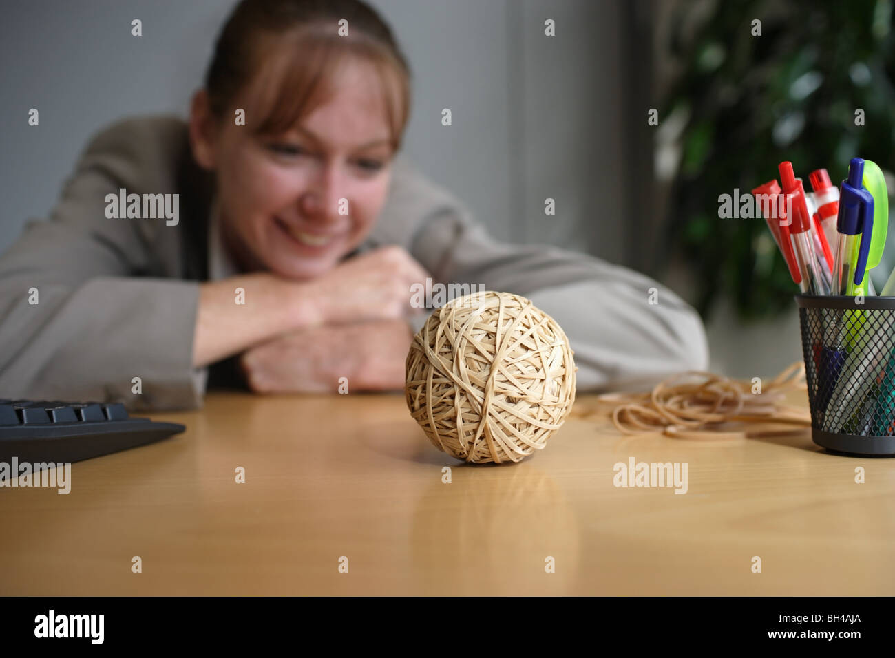 A businesswoman looking at a hand made rubber band ball on an office