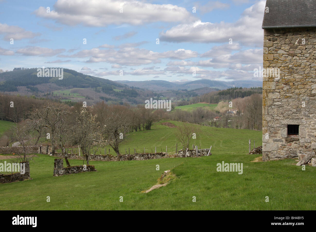View over the hilly Limousin landscape with a small orchard and building in early spring. Stock Photo
