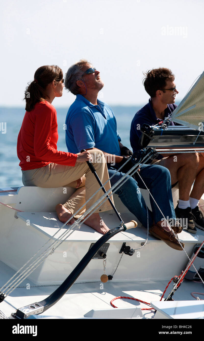 Three adults enjoying a sunny day on board a daysailer on Casco Bay, Maine. Stock Photo