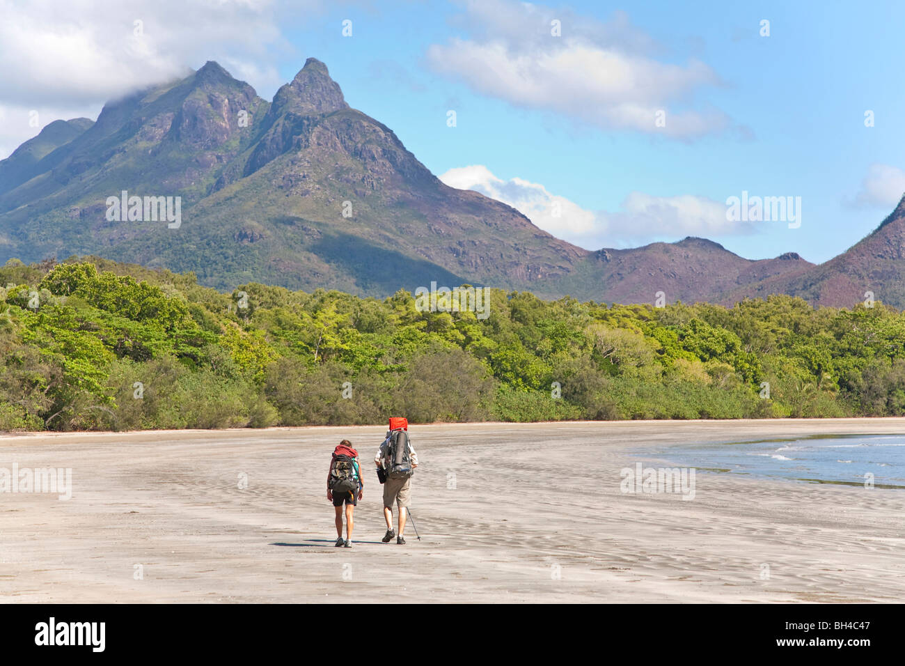 A man and woman with their baby hike along Zoe Bay, Hinchinbrook Island, Queensland, Australia. Stock Photo