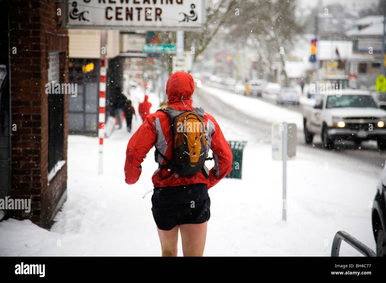 A male runner with a backpack runs down a city street while wearing