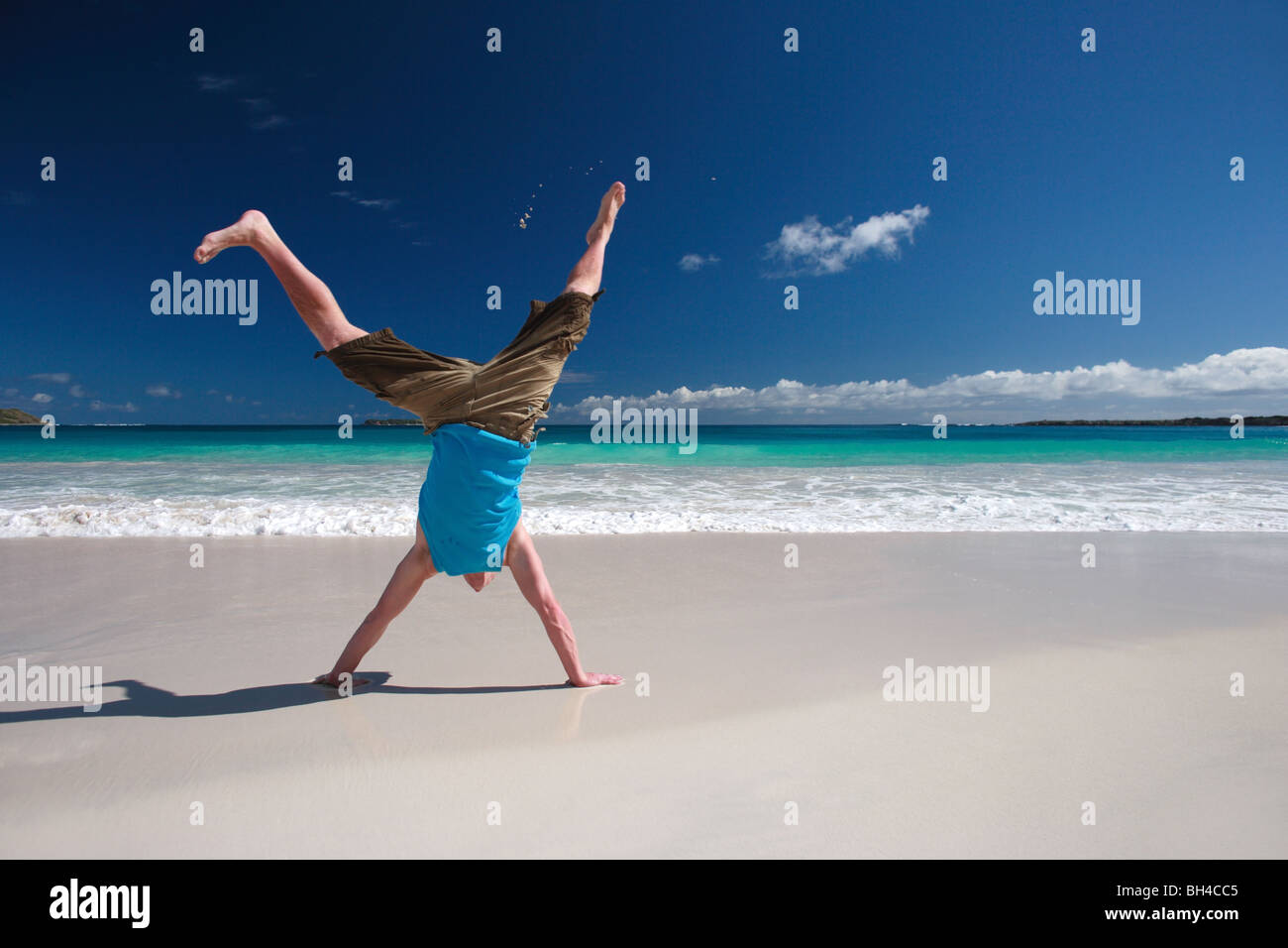 Young man performing a handstand on a deserted tropical beach Stock Photo