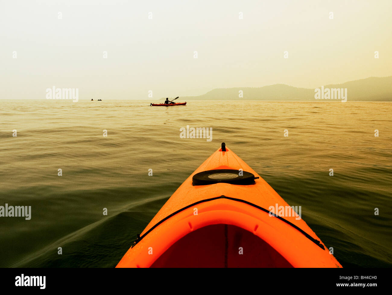 The view of a person kayaking on the lake during a smoky afternoon, in Lake Tahoe, Nevada. Stock Photo