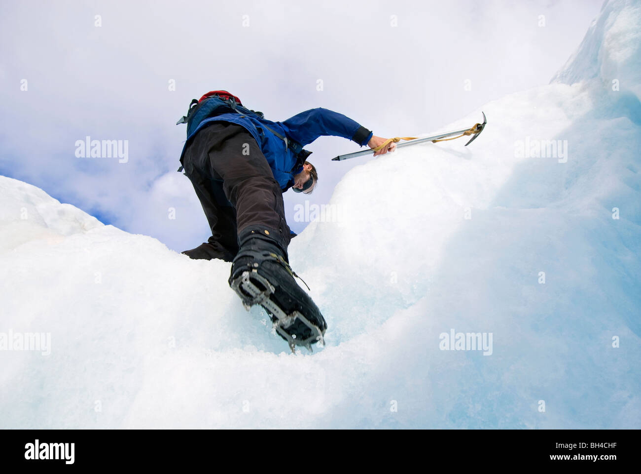 A young man climbs up steps on a glacier with crampons and an ice axe in Franz Josef, New Zealand. Stock Photo