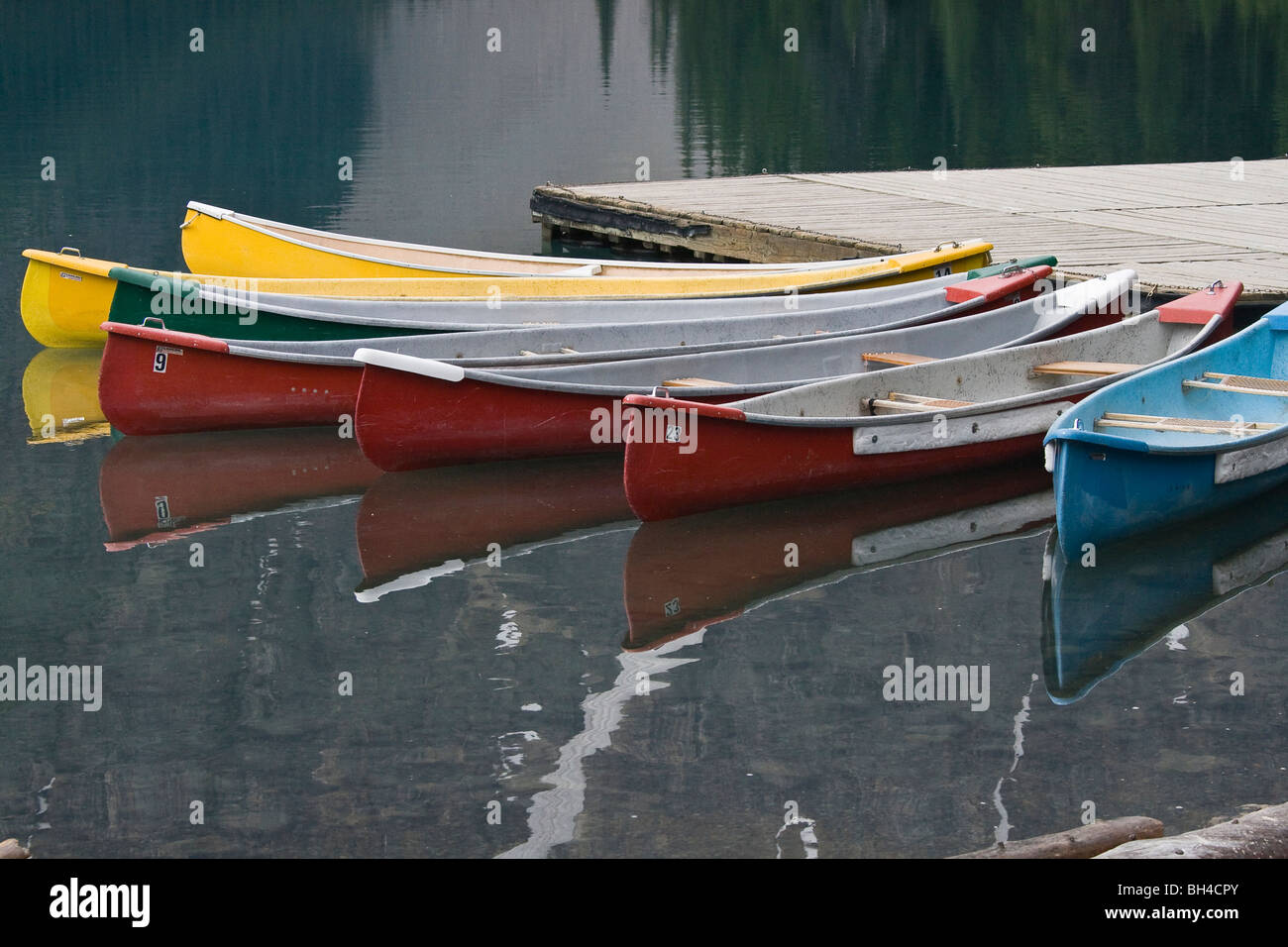 Docked boats with their reflections on Moraine lake in the early morning. Stock Photo