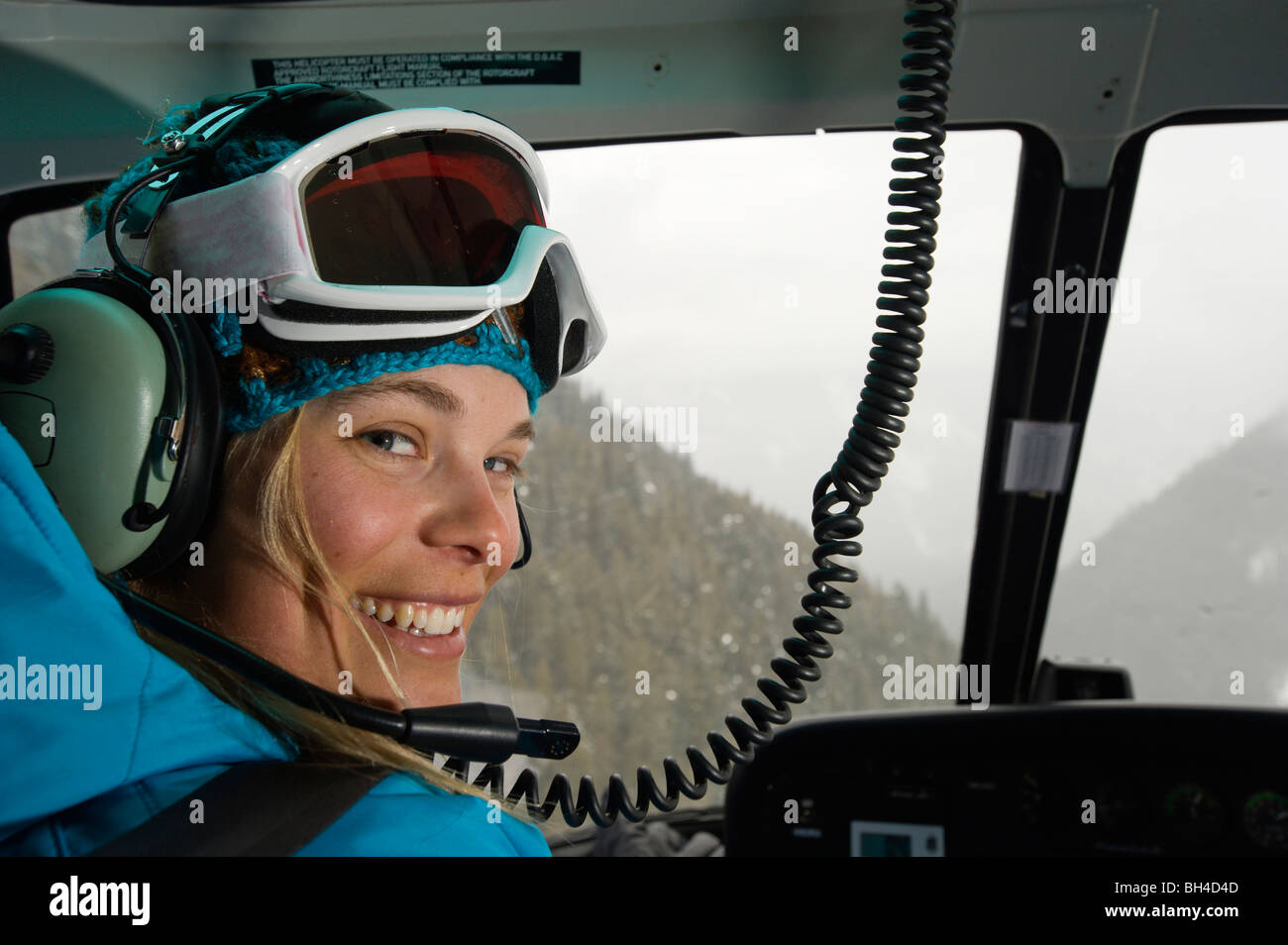 A woman skier smiles as she plays co-pilot while helicopter skiing in the Selkirk Mountains, Canada. Stock Photo
