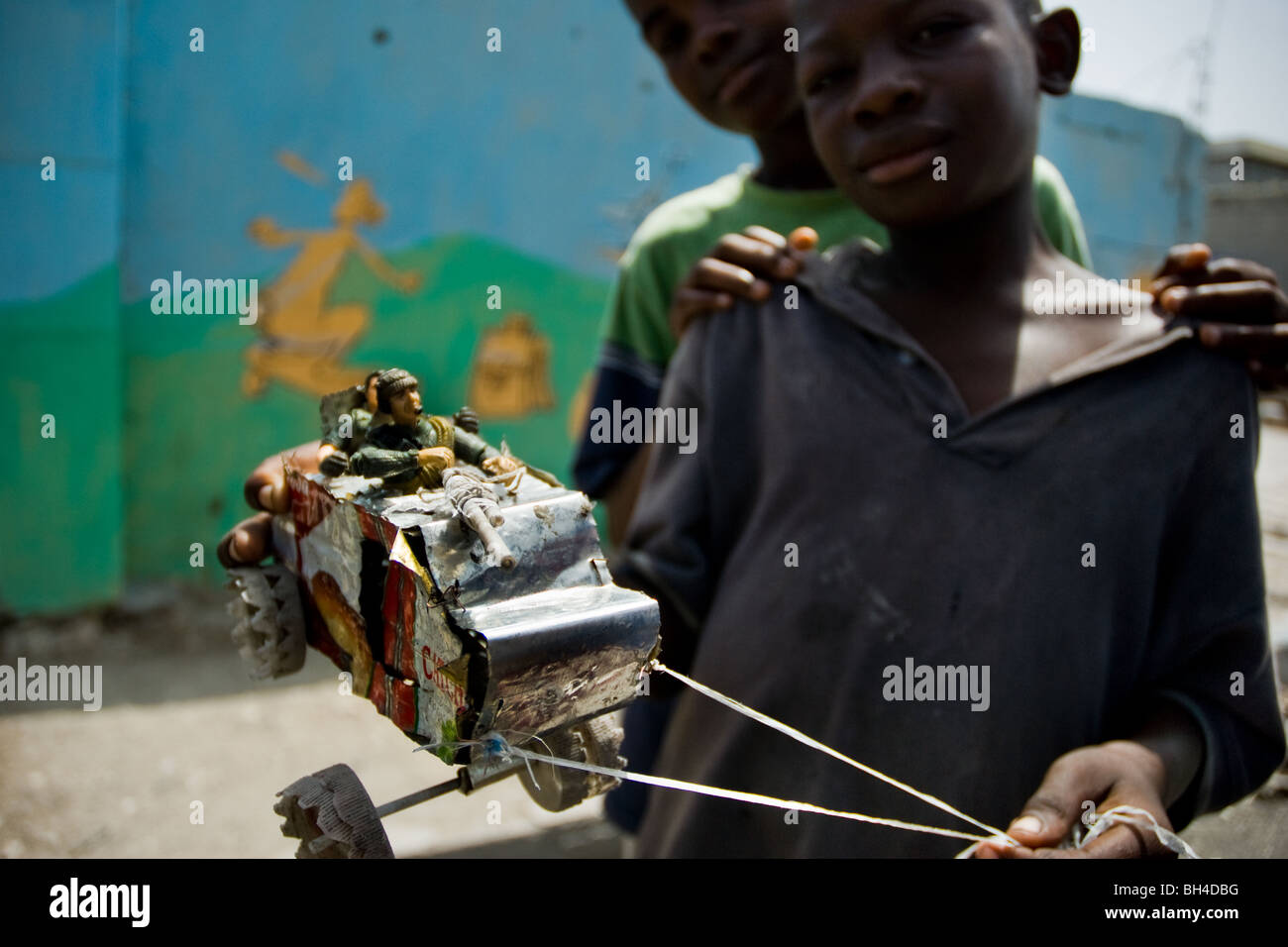 A young Haitian boy showing a home made armoured vehicle toy on the street of the slum of Cité Soleil. Stock Photo