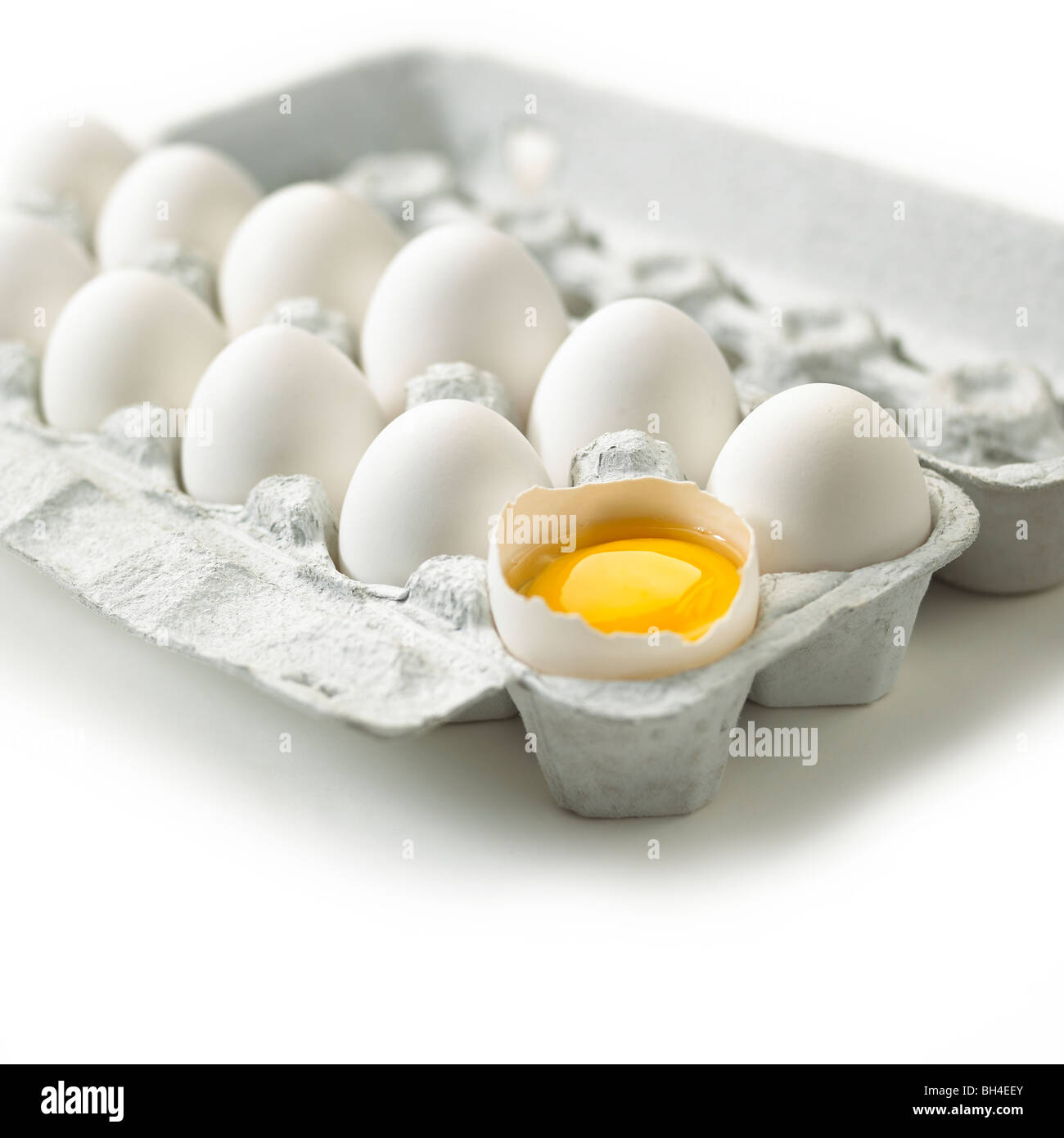 Broken white egg in a carton on a white background Stock Photo