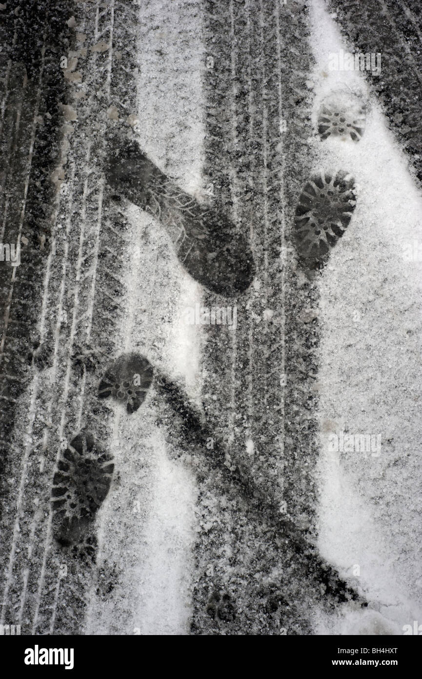 Tyre tracks and footprints on a snow covered road Stock Photo - Alamy