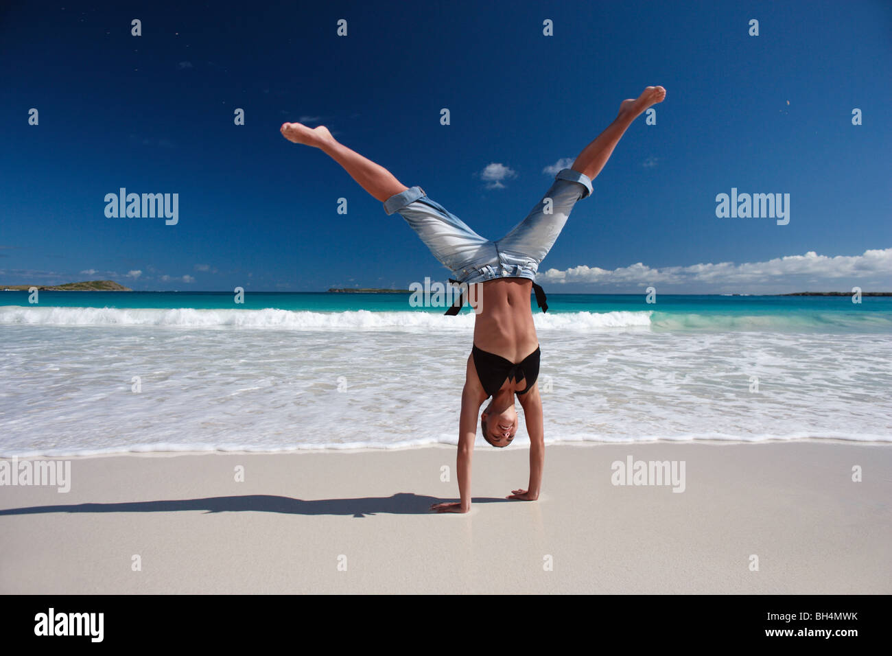 Young woman performing a hand stand on a deserted tropical beach Stock Photo