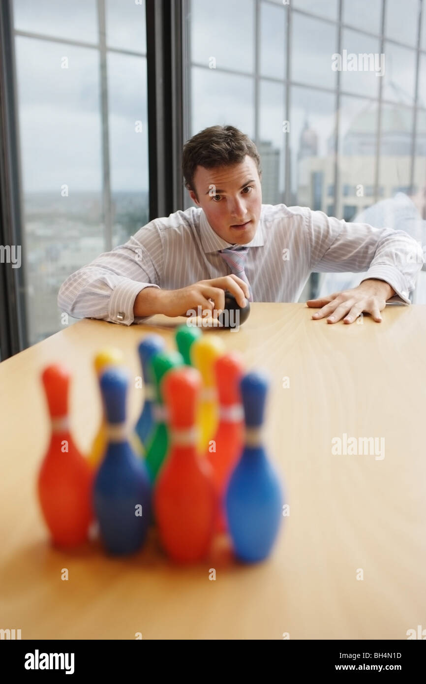 Businessman playing with miniature toy skittles on office desk Stock Photo