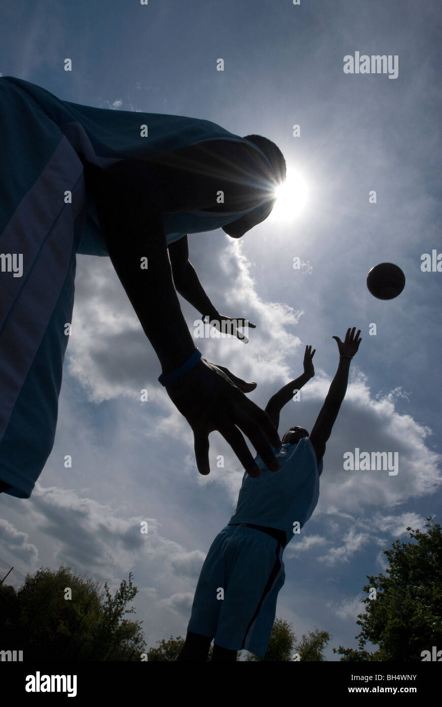 Basketball players are silhouetted in a blue UK Stock Photo