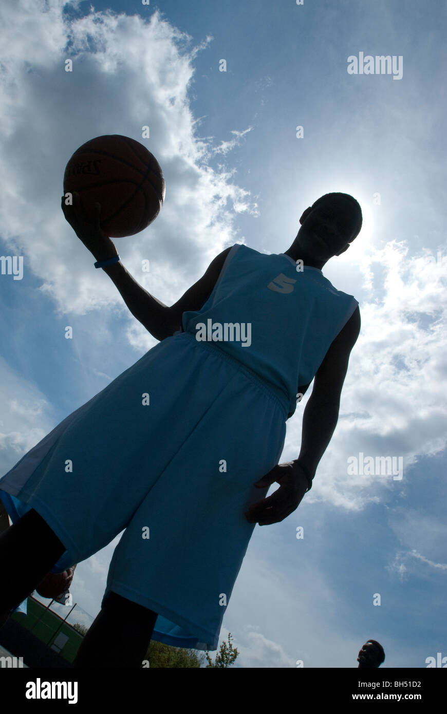 Basketball players are silhouetted in a blue UK Stock Photo