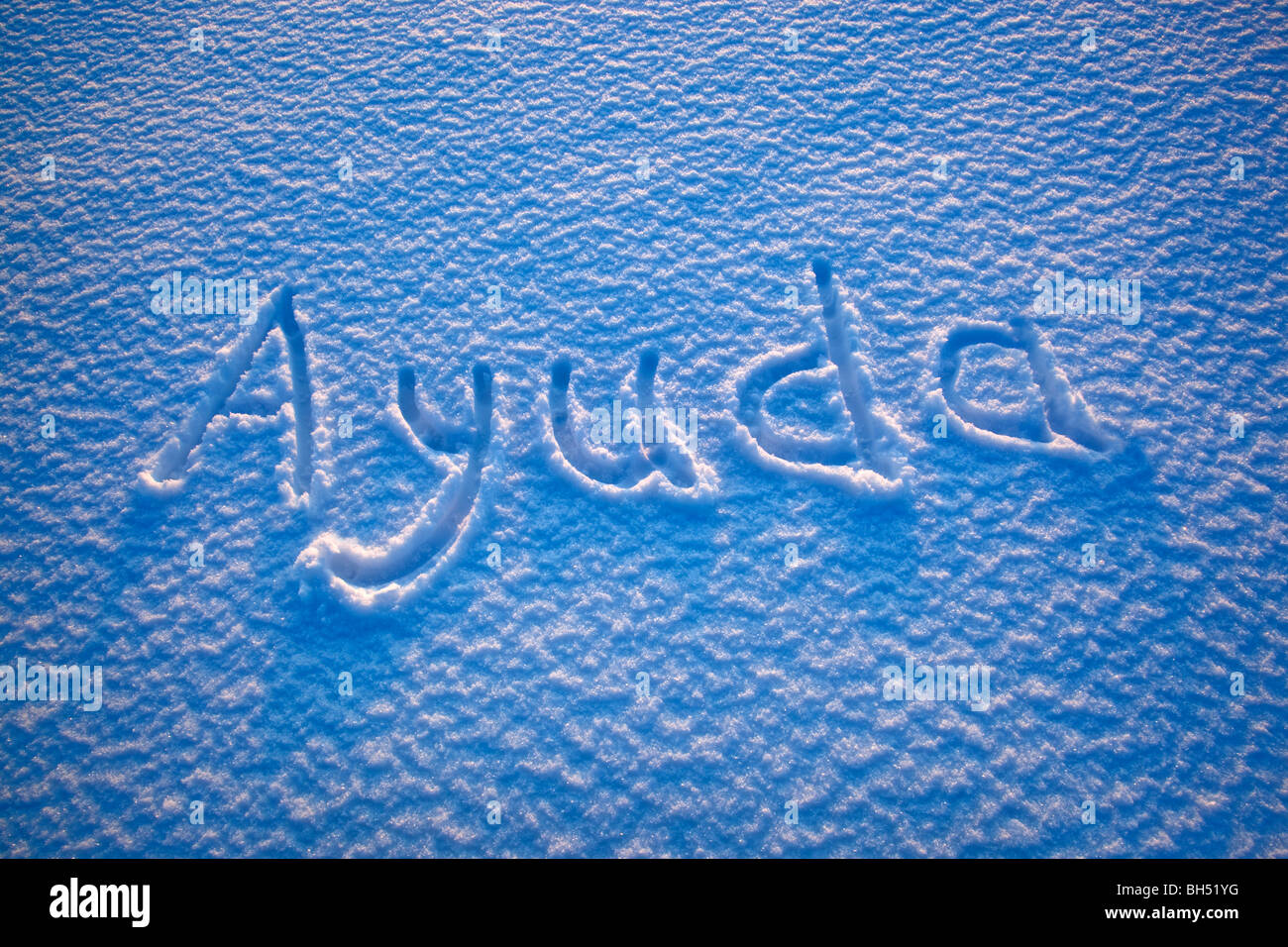 The Spanish word for 'help' spelled out in the snow Stock Photo