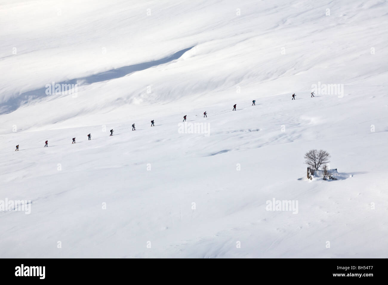 A group of snowshoe hikers walking in line in Winter (Auvergne-France). Groupe de randonneurs se déplaçant en raquettes l'hiver. Stock Photo