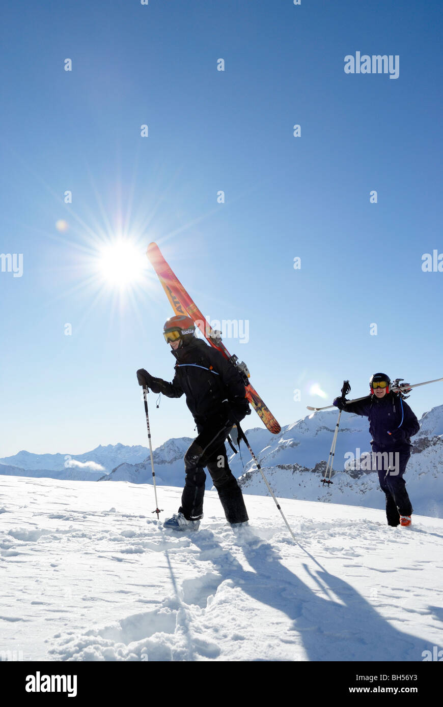 Two skiers walking and carrying their skis on off-piste terrain, Gemsstock, Andermatt, Switzerland Stock Photo