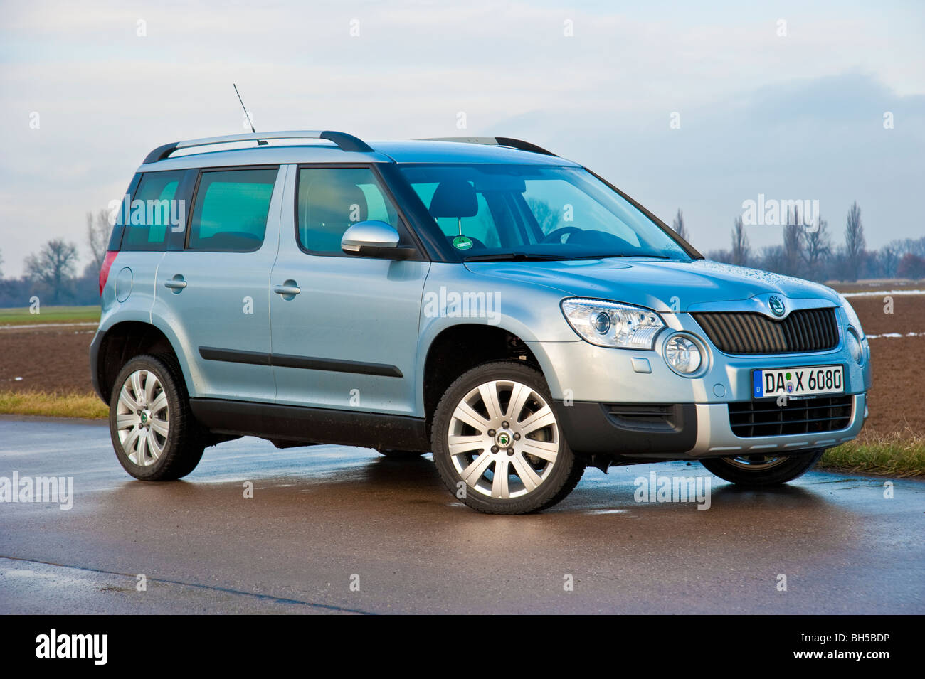 Front, side view Skoda Yeti SUV, 2010 model in light blue metallic parked on a street next to a field Stock Photo
