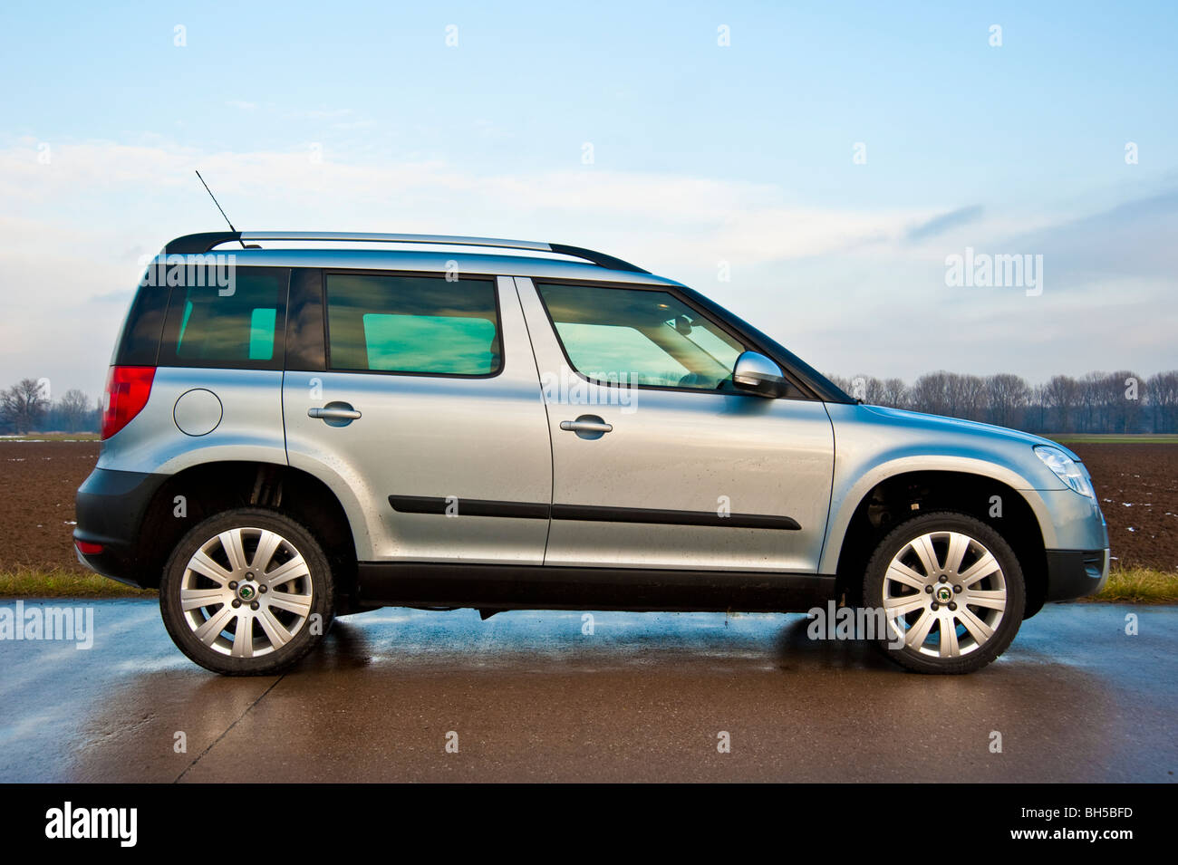 side view Skoda Yeti SUV, 2010 model in light blue metallic parked on a street next to a field Stock Photo