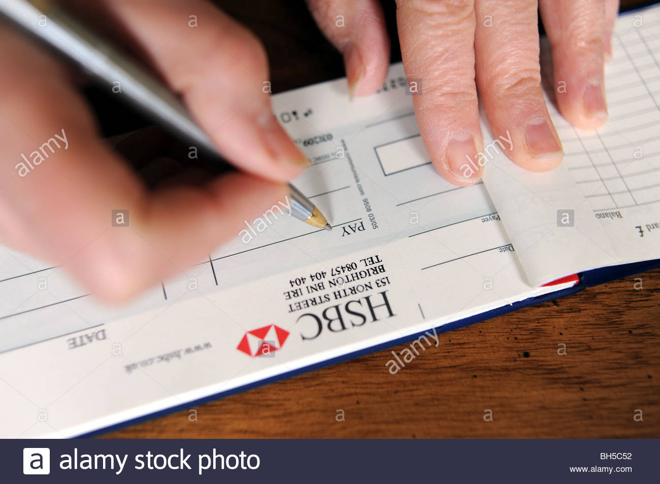 Woman Writing Out A Cheque From Her Bank Chequebook Stock Photo