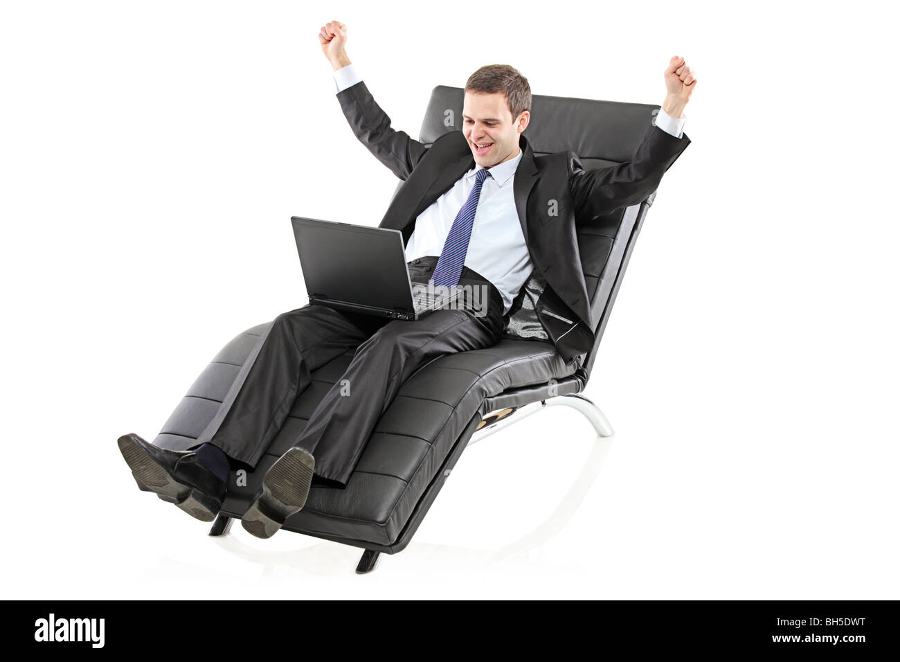 Businessman lying on a black leather chair with a laptop in his lap Stock Photo
