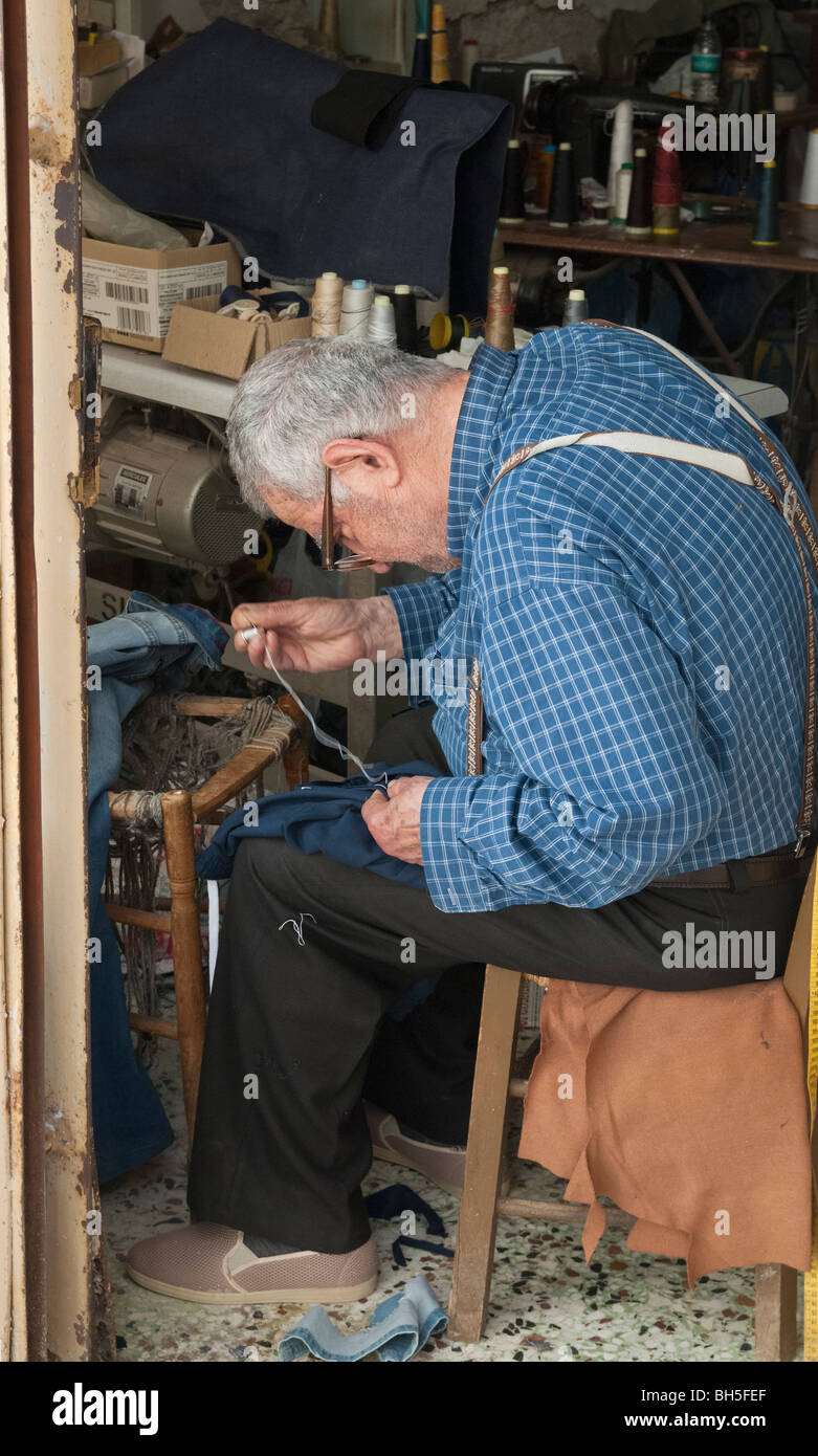 Old tailor at work sewing with needle and thread in Poros Town, Poros Island, Greece Stock Photo