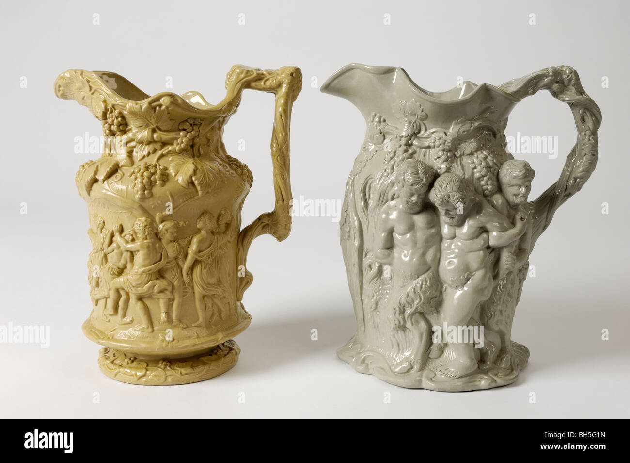 Two antique 19th C. English stoneware relief moulded jugs with  Bacchanalian ornament. Figures: infant Bacchus, old Silenus. Stock Photo