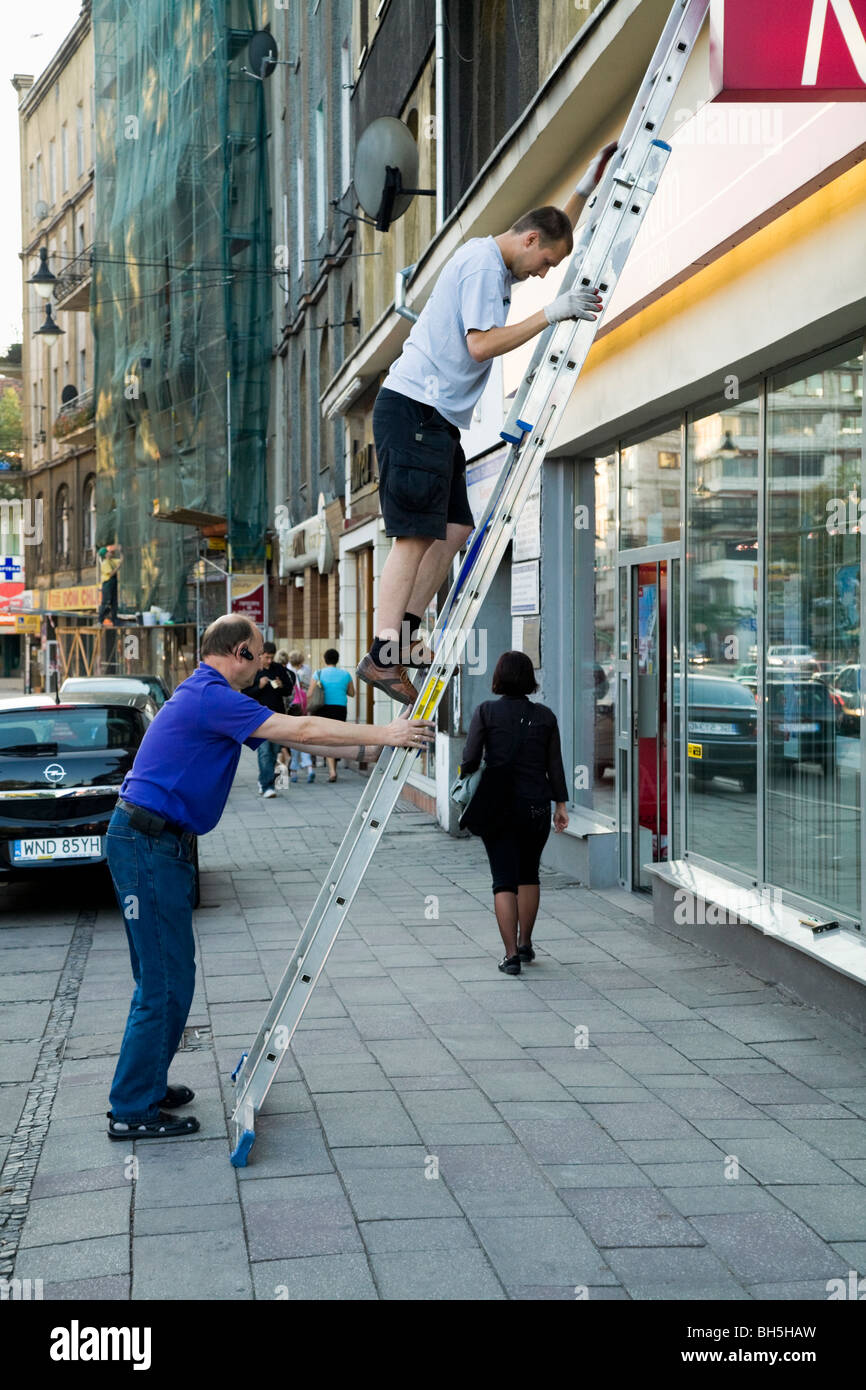 Pedestrian having walked under a ladder being used by workmen. (51) Stock Photo