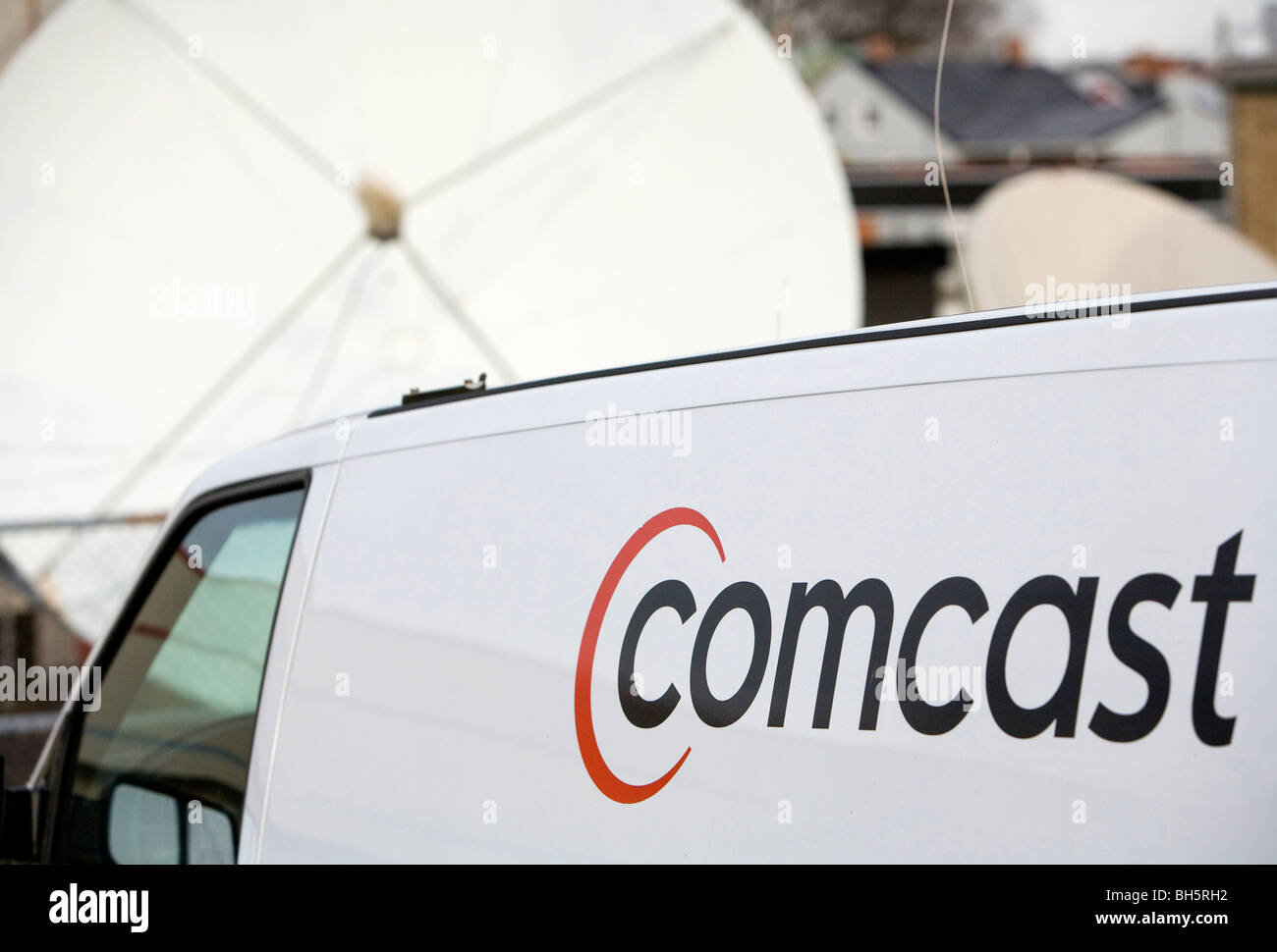 A Comcast Corporation logo on a vehicle in front of a satellite dish.  Stock Photo