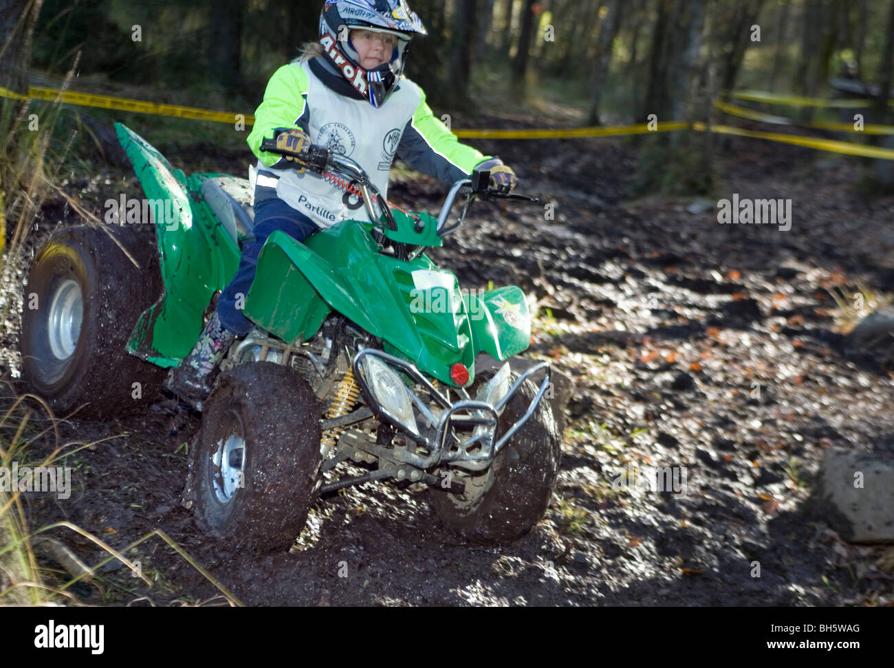 4 wheel trial competition. A young girl in protective wear rides all terrain vehicle off road Stock Photo